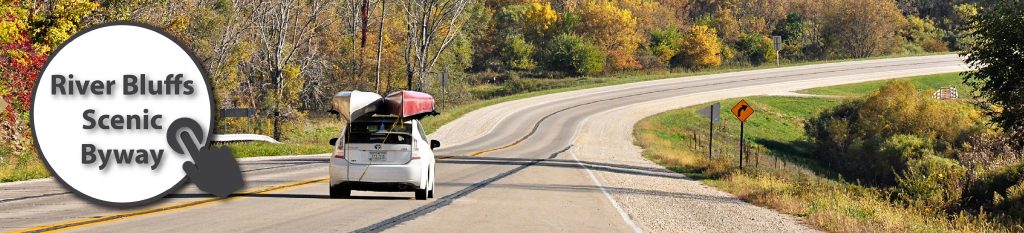 White car with canoes on top on a scenic highway